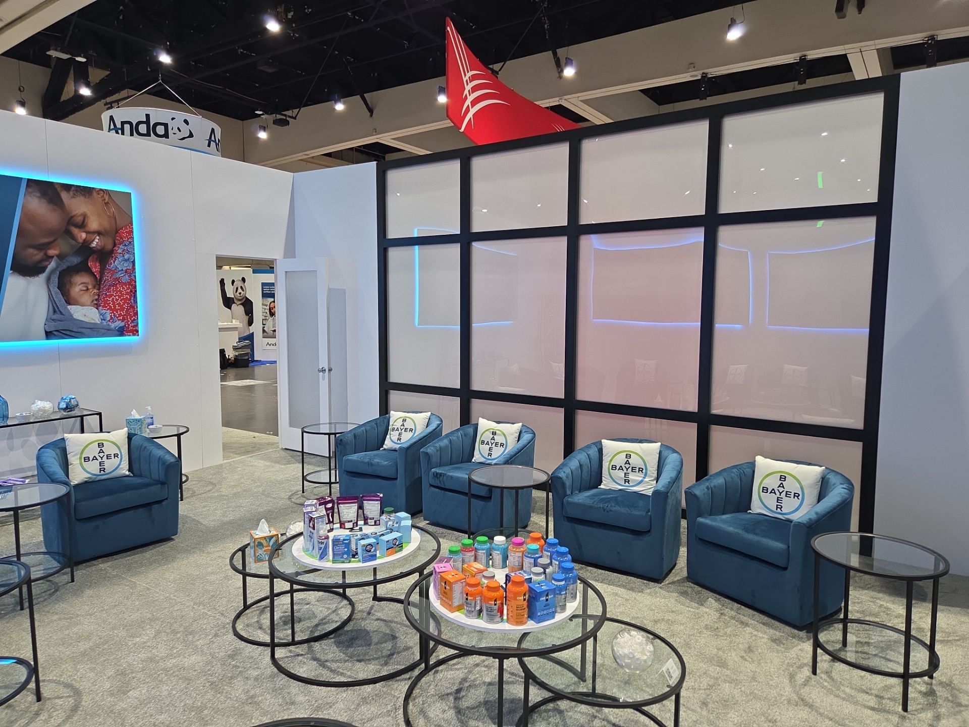 Booth interior — frosted glass wall with LED accent lighting, lounge seating, and curated product display